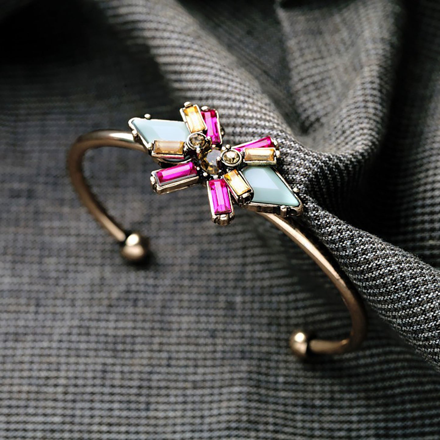 Open bracelet in gold with geometric crystal decorations.