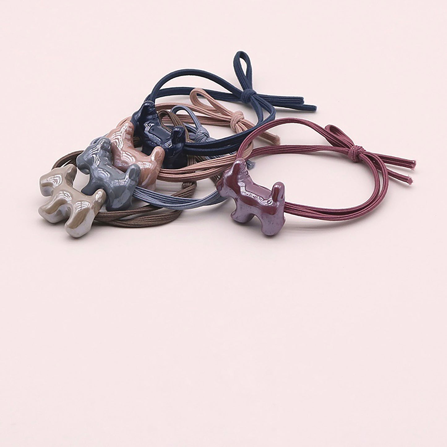 Goma para el cabello rosa suave con un colgante en forma de perro con acabado brillante.