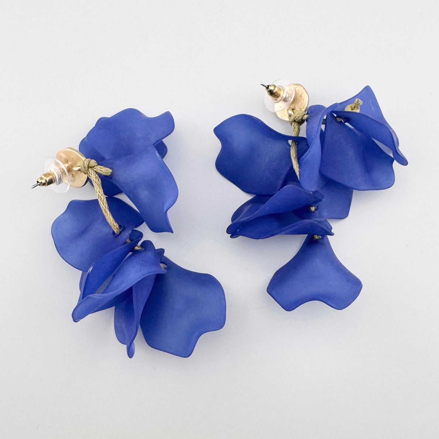 Boucles d'oreilles pendantes avec pétales de fleurs bleues et accents dorés.