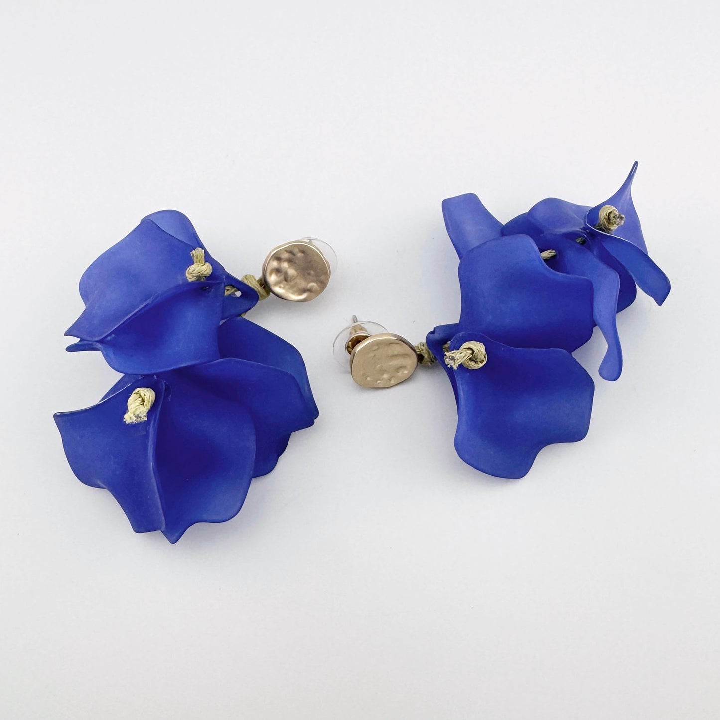 Pendientes colgantes con pétalos de flores azules y detalles dorados.