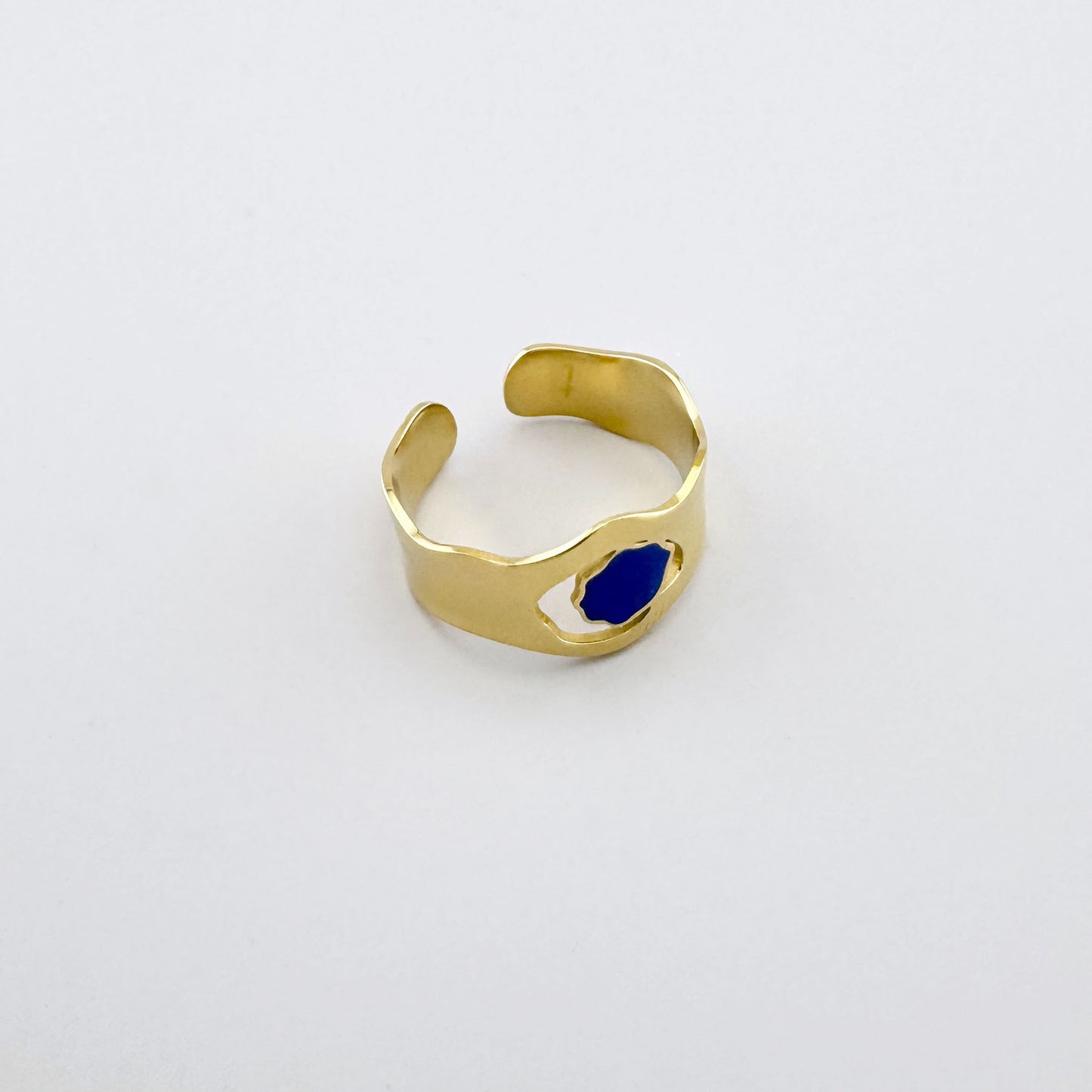Gold-plated stainless steel ring with a wavy shape, cutout detail, and blue enamel, French brand Ikita.