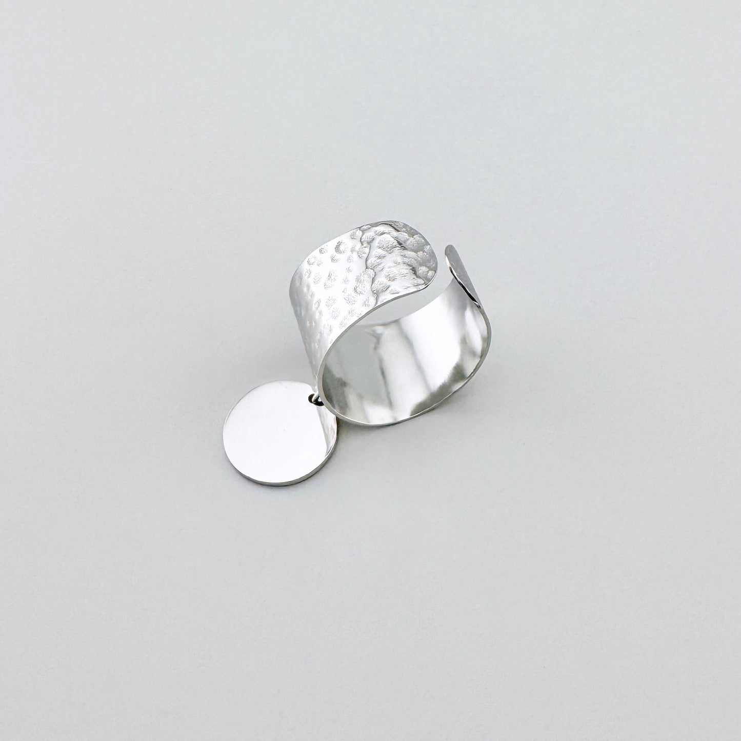 Silver stainless steel ring with a wide band and a textured medallion, French brand Ikita.