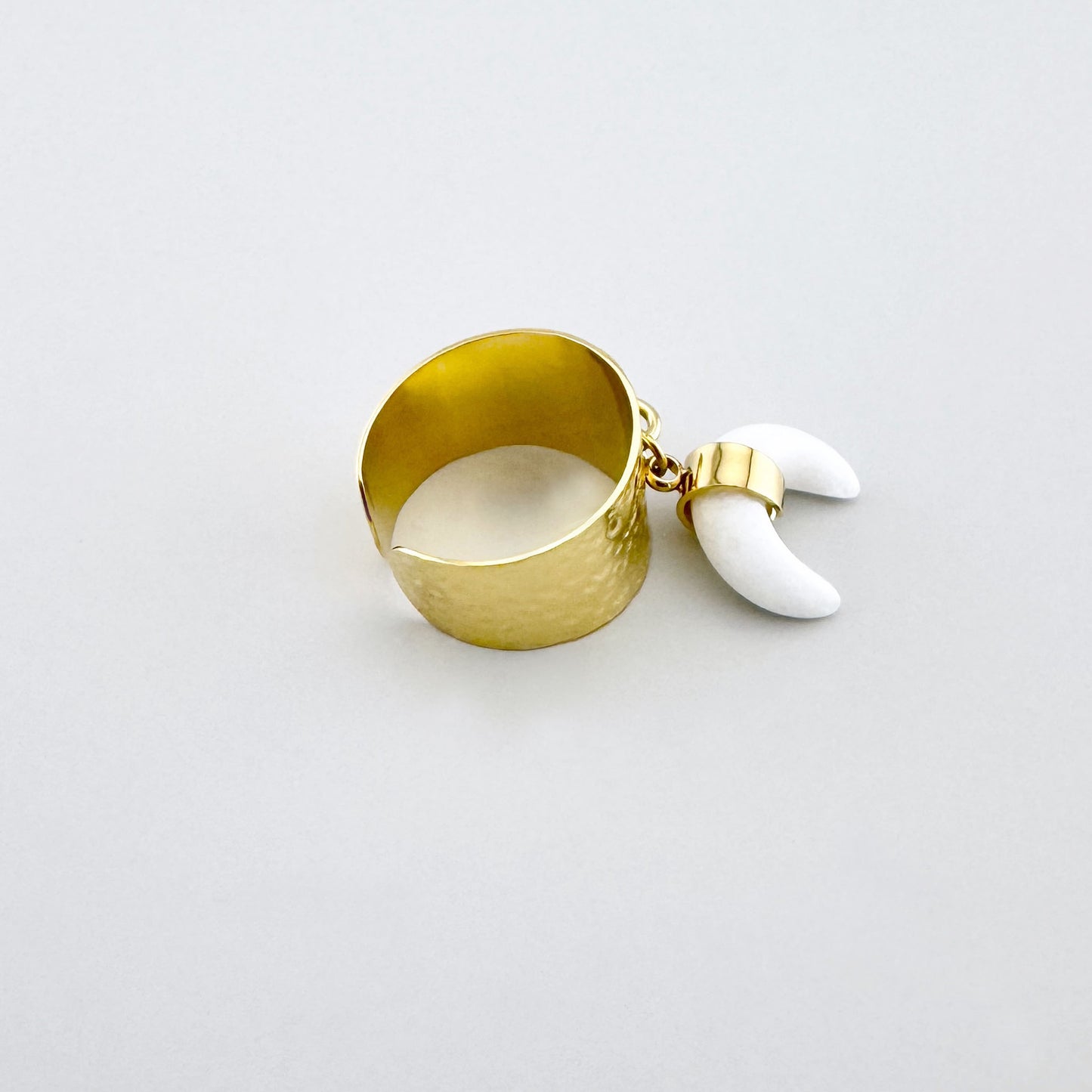 Goldfarbener Ring mit breitem Band und weißem Anhänger in Form eines Halbmondes, französische Marke Ikita.