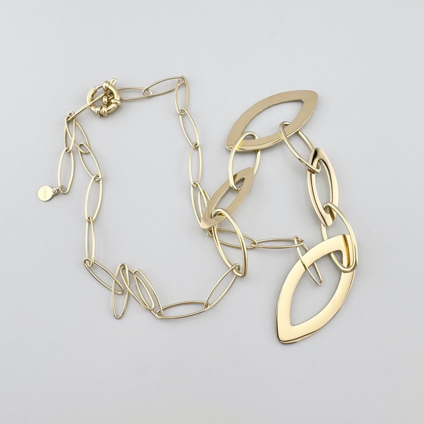 Gold-plated stainless steel necklace with elliptical links and textured elements, French brand Ikita.