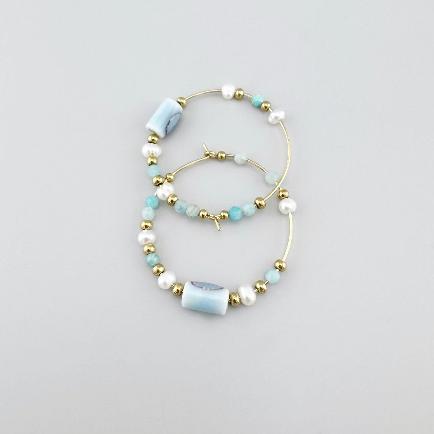 Aros con perlas, piedras facetadas en azul y detalles de cerámica, marca francesa Ikita.