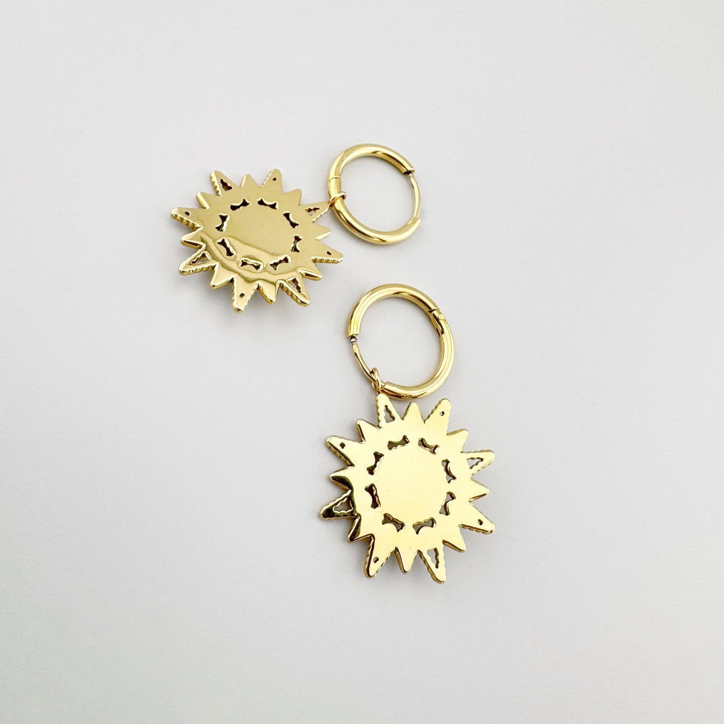Pendientes en forma de estrella dorada con piedra negra y detalles esmaltados, marca francesa Ikita.