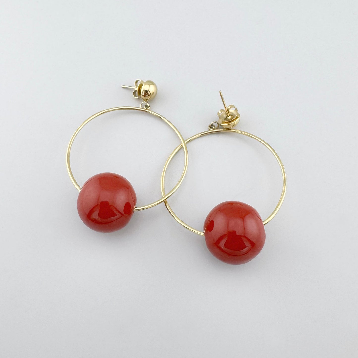 Boucles d’oreilles créoles avec une grande perle rouge brillante, marque française Ikita.