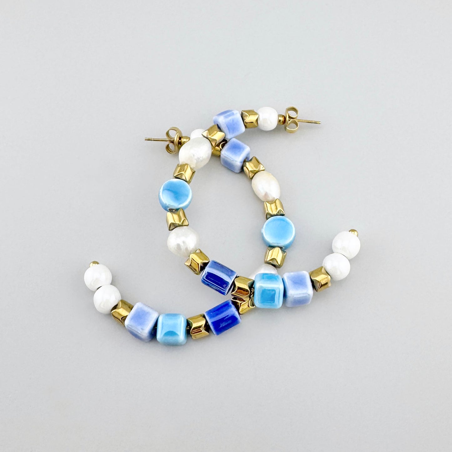Pendientes de aro con cerámica y perlas en tonos azul y blanco, adornados con cuentas doradas, marca francesa Ikita.