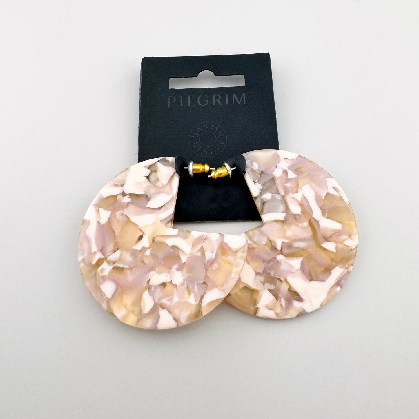 Boucles d'oreilles en forme de croissant en acétate avec motif marbré beige et blanc, marque danoise Pilgrim.