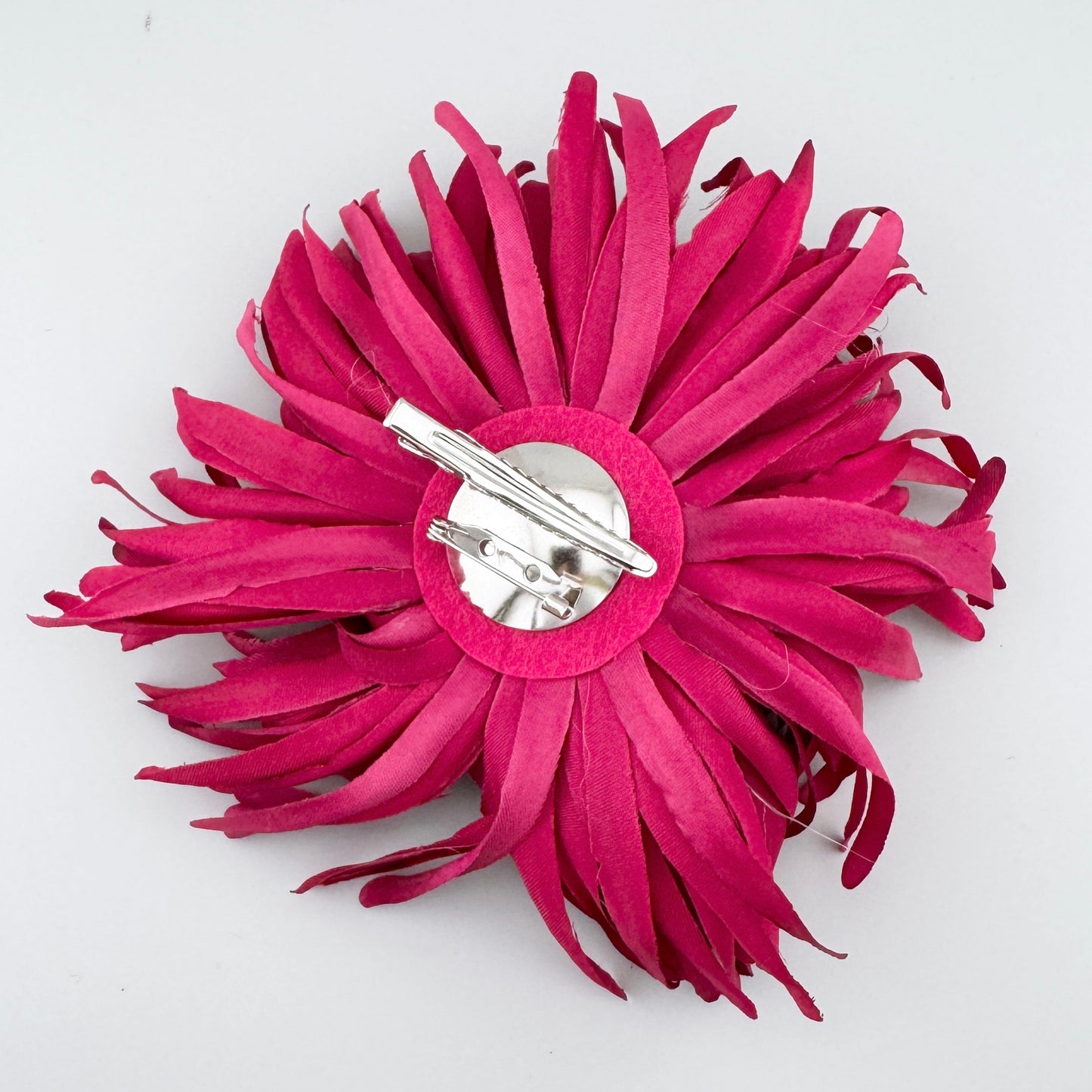 Broche con forma de crisantemo en tela color fucsia intenso, de la marca española Sonata.