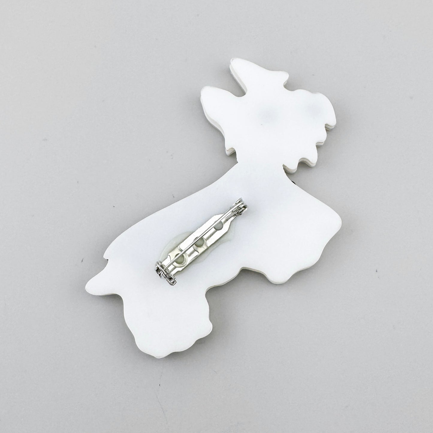 Broche con forma de perro en acrílico con efecto mosaico y abrigo beige satinado, de la marca española Sonata.