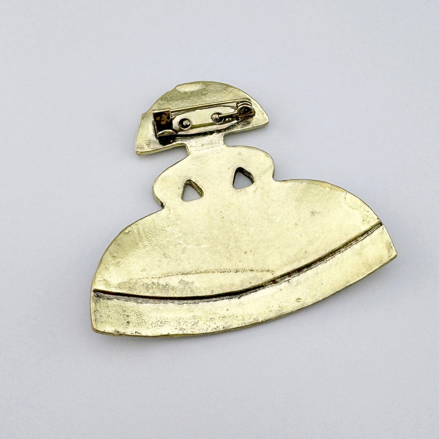 Broche con forma de figura en vestido, hecho de metal con acabado dorado y esmalte en tonos azul-verde.