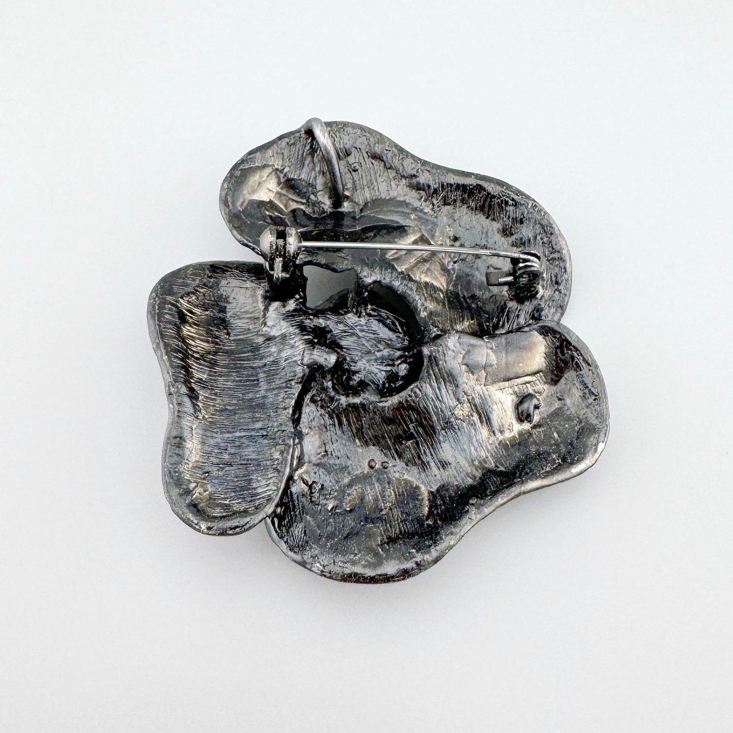 Metal flower-shaped brooch with an oxidized finish and a large green crystal, Spanish brand Sonata.