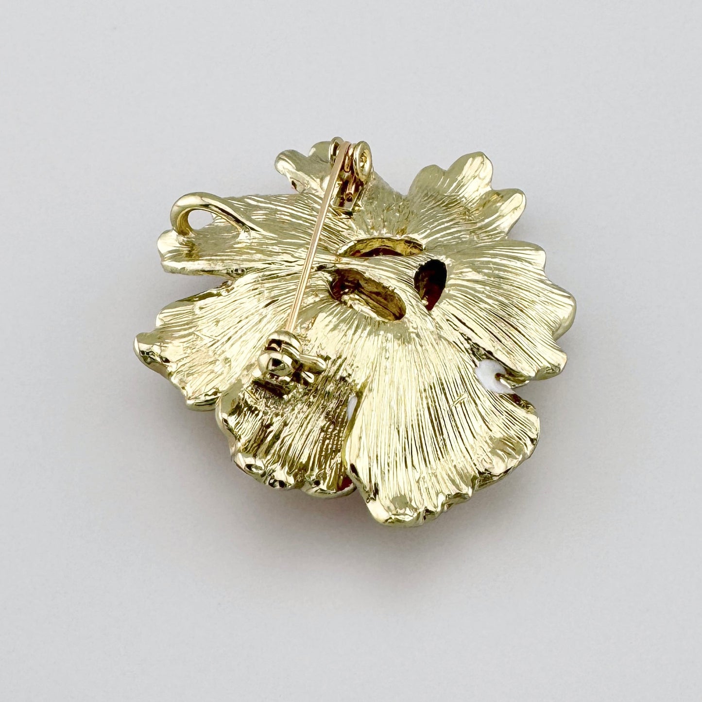 Broche en forma de flor con pétalos esmaltados en tonos blancos y naranjas, con una perla artificial brillante en el centro, marca española Sonata.