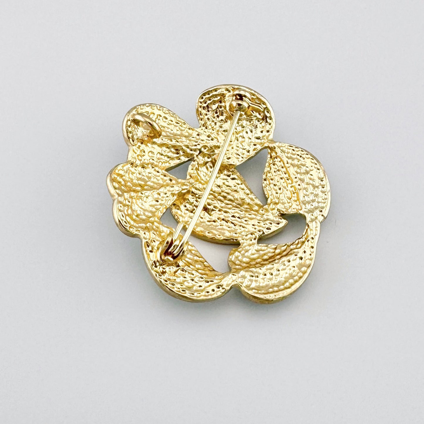 Grüne Brosche in Blattform mit marmoriertem Muster und goldenen Akzenten.