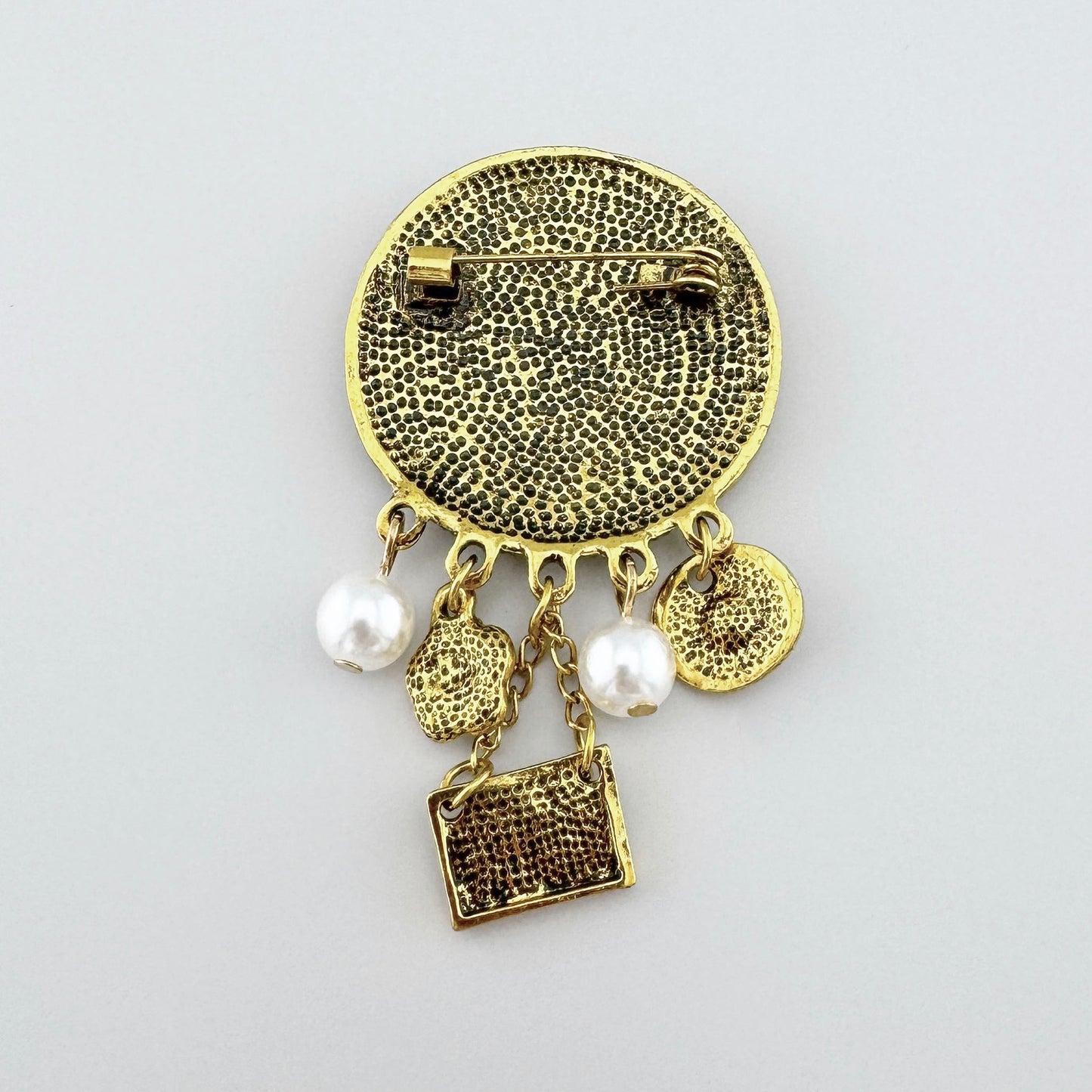 Broche élégante en ton doré avec médaillon, ornée de perles synthétiques et de pendentifs suspendus, marque espagnole Sonata.