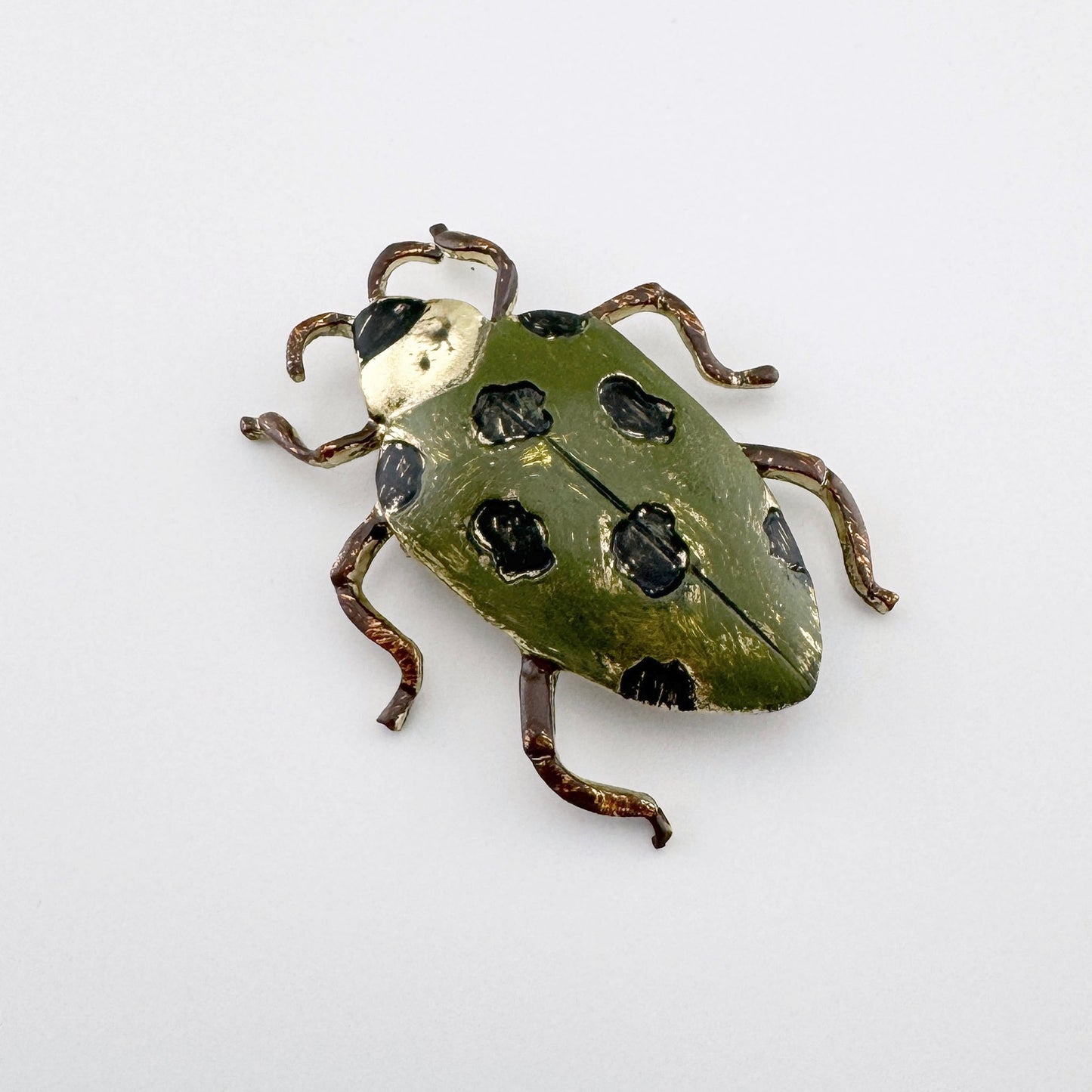 Broche en forme d’insecte, en métal avec émail vert et détails noirs.
