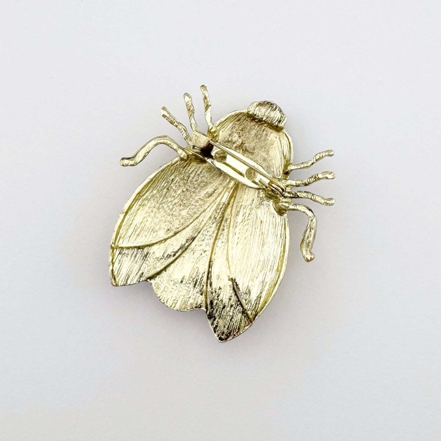 Broche con forma de escarabajo en tonos amarillos y marrones, con detalles pintados a mano.