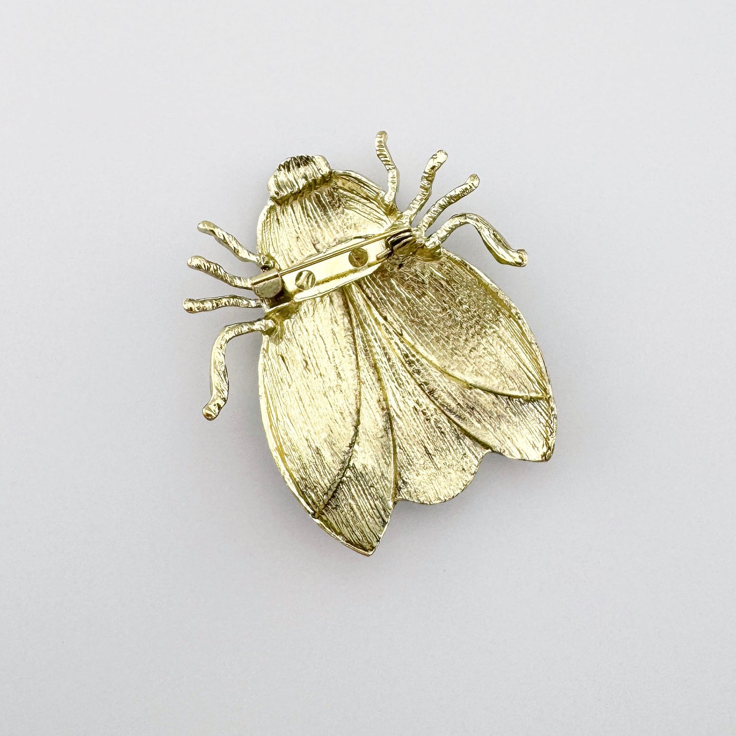 Green beetle-shaped brooch with orange and black accents, hand-painted.