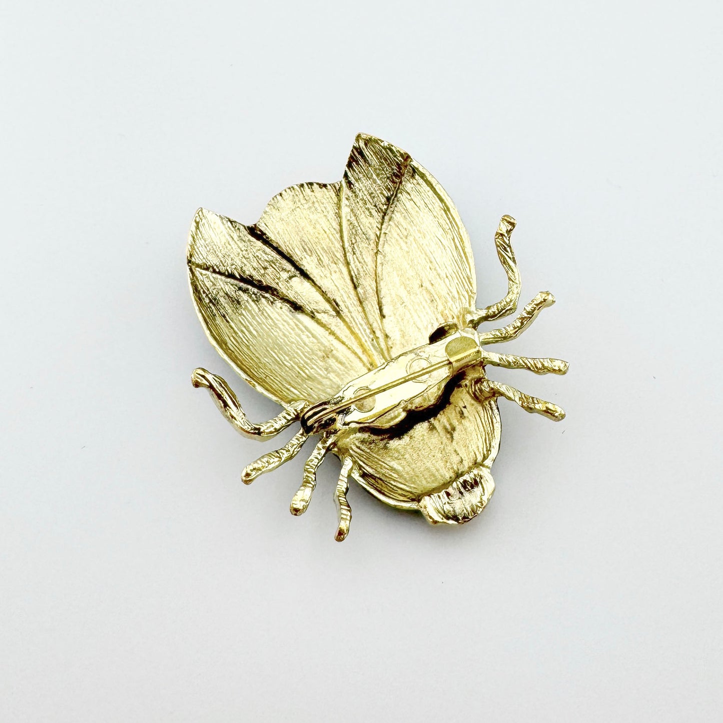 Broche con forma de escarabajo, decorado con esmalte en tonos azul, rosa y amarillo.