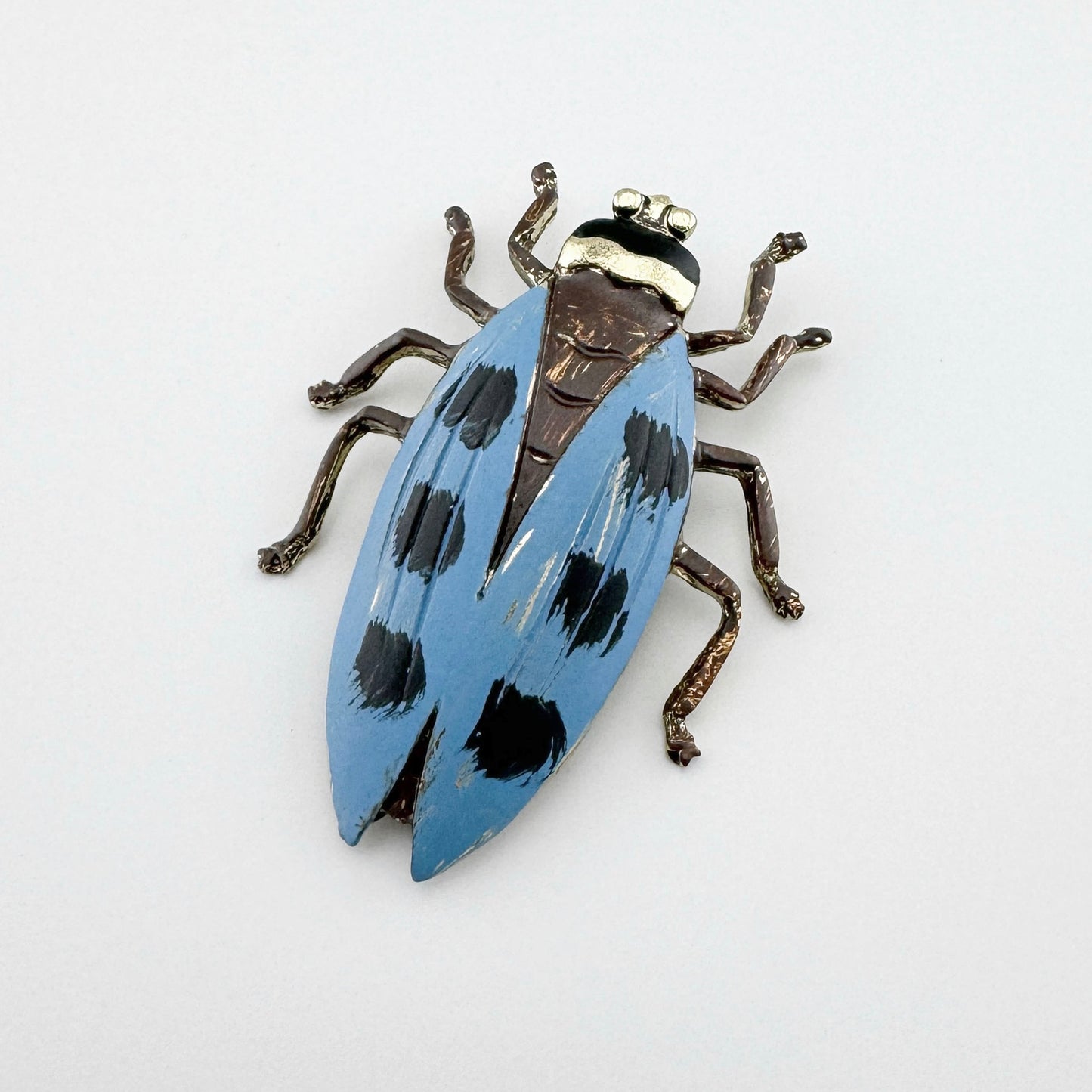 Käferförmige Brosche, handbemalt in Blau mit schwarzen und goldenen Akzenten.