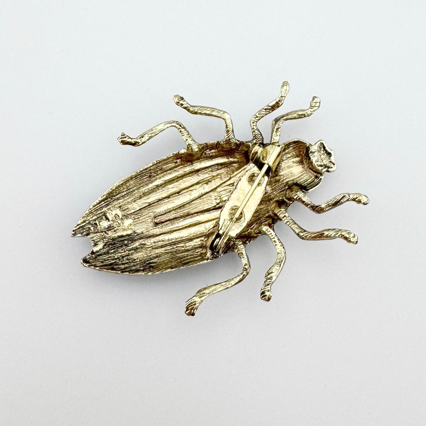 Broche en forma de escarabajo, pintado a mano en azul con detalles negros y dorados.
