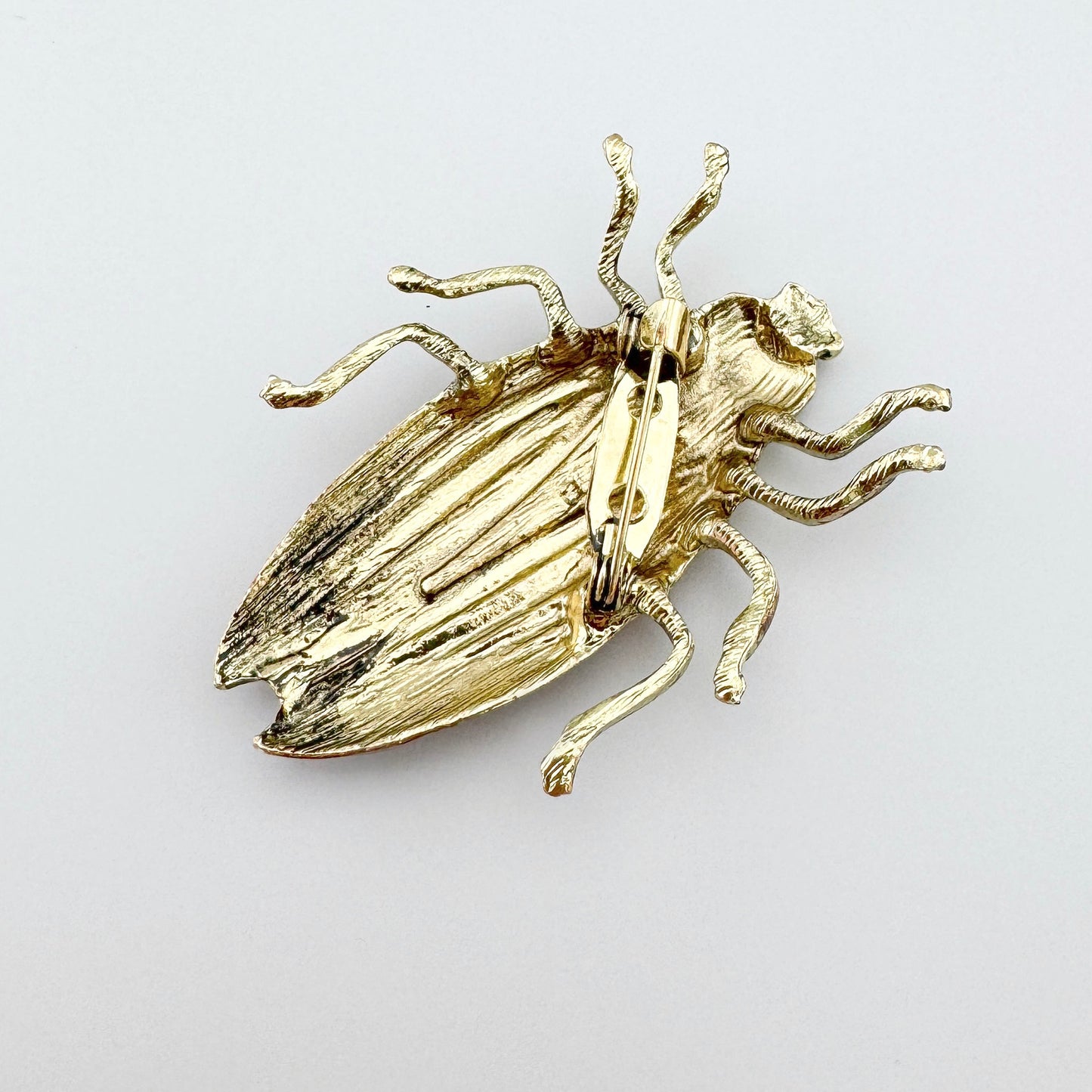 Käferförmige Brosche, handbemalt in Rot mit schwarzen und goldenen Details.