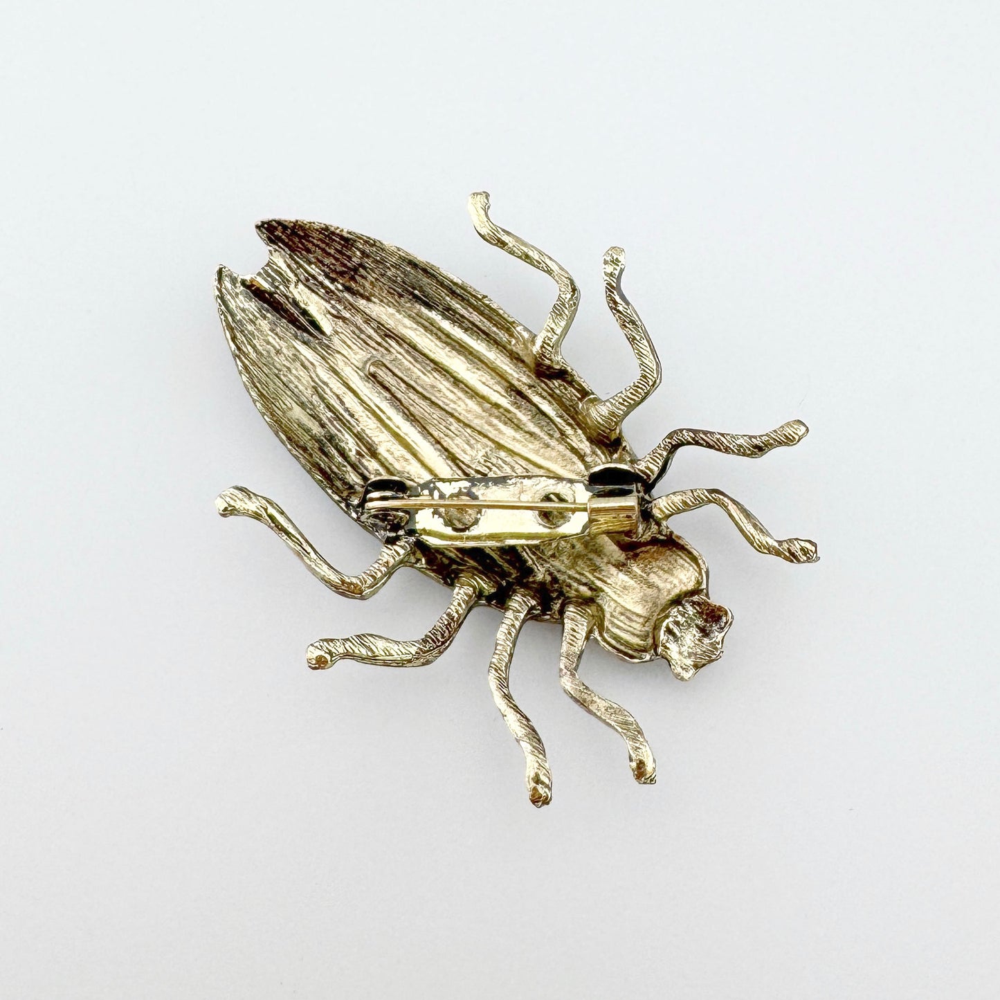 Брошь в форме жука, вручную раскрашенная в зеленых и коричневых тонах.