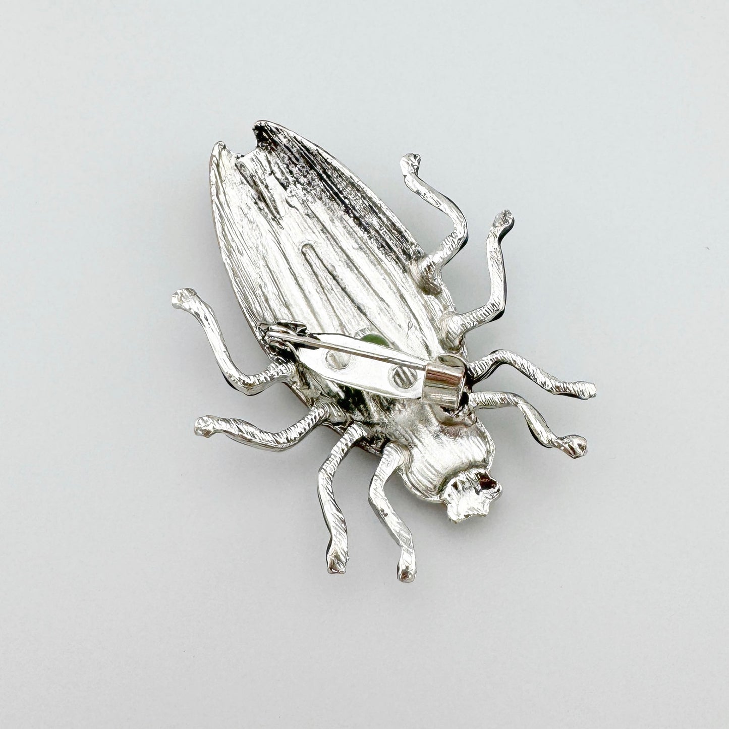 rooch in the shape of an insect, hand-painted in shades of green, pink, and gold.