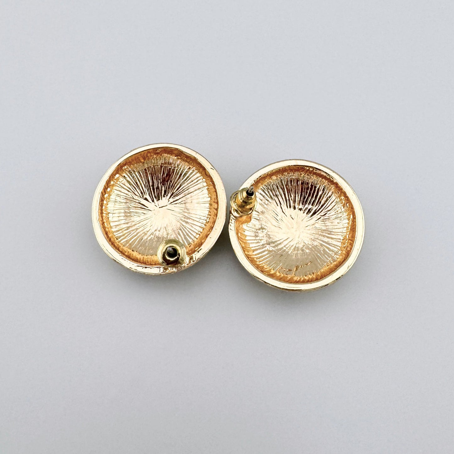 Runde Ohrringe mit Rautenmustern in Schwarz und Creme, goldene Oberfläche.