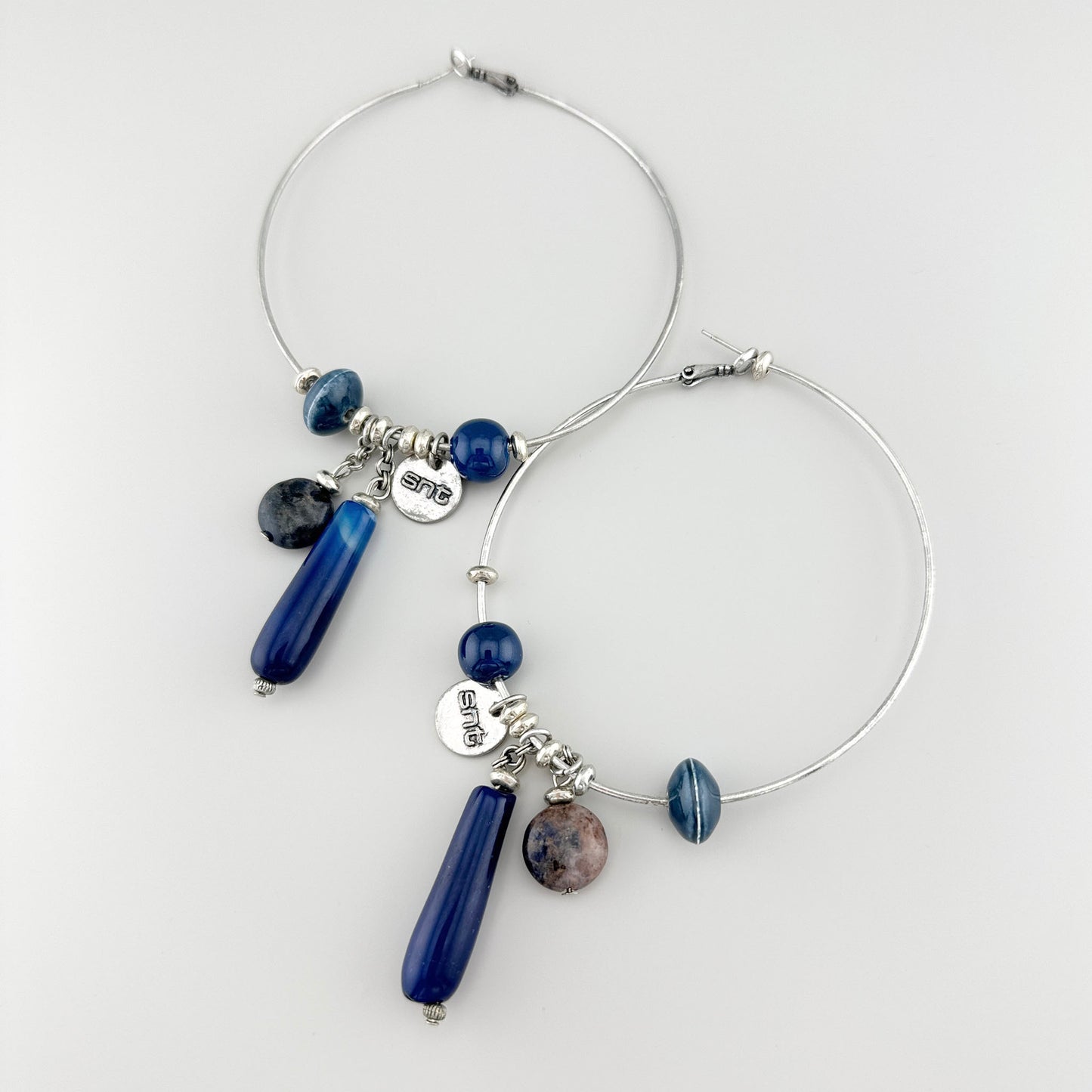 Hoop earrings in silver with blue stones and decorative pendants.