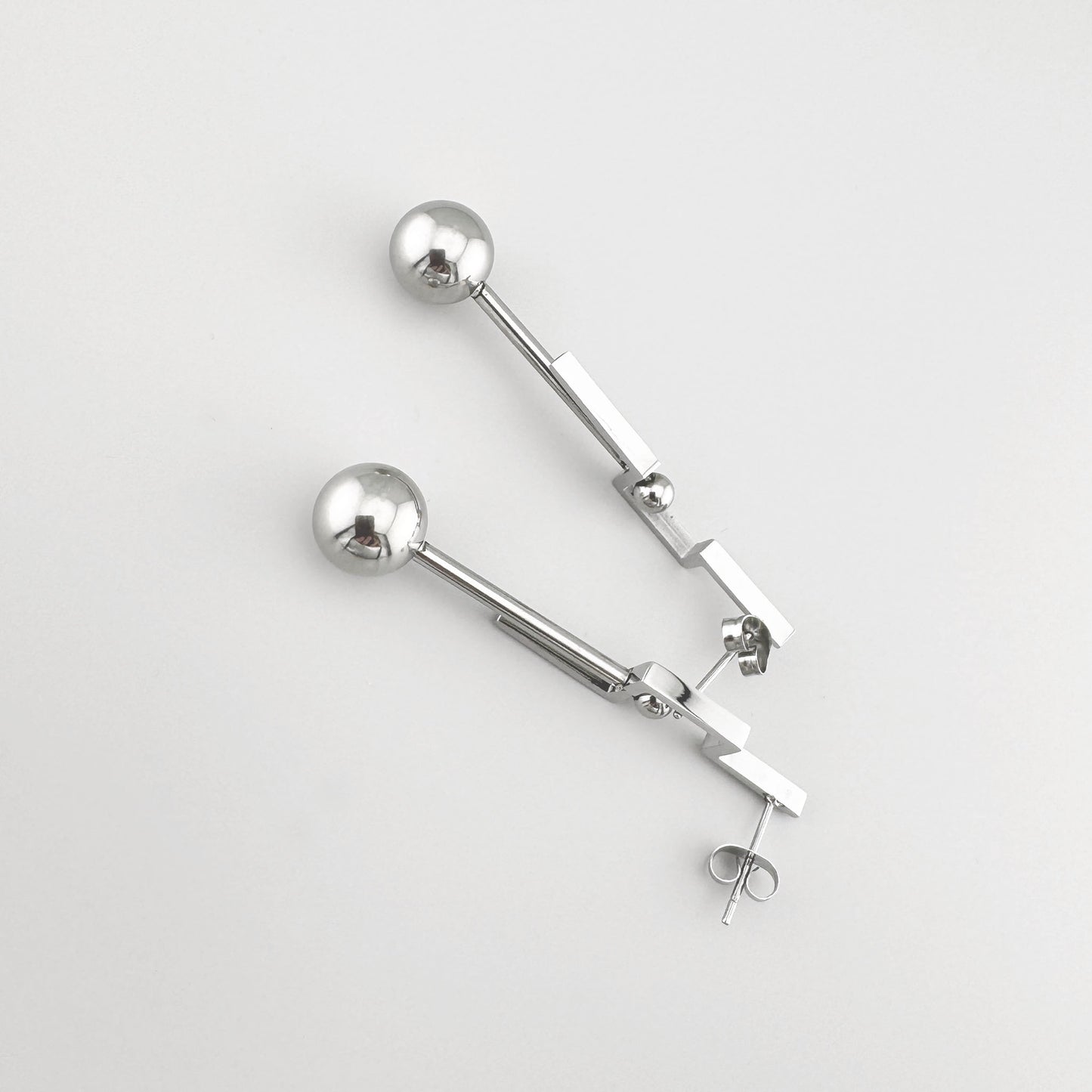 Geometric earrings in polished silver metal, featuring rectangular elements and beads. Brand Maravillas.