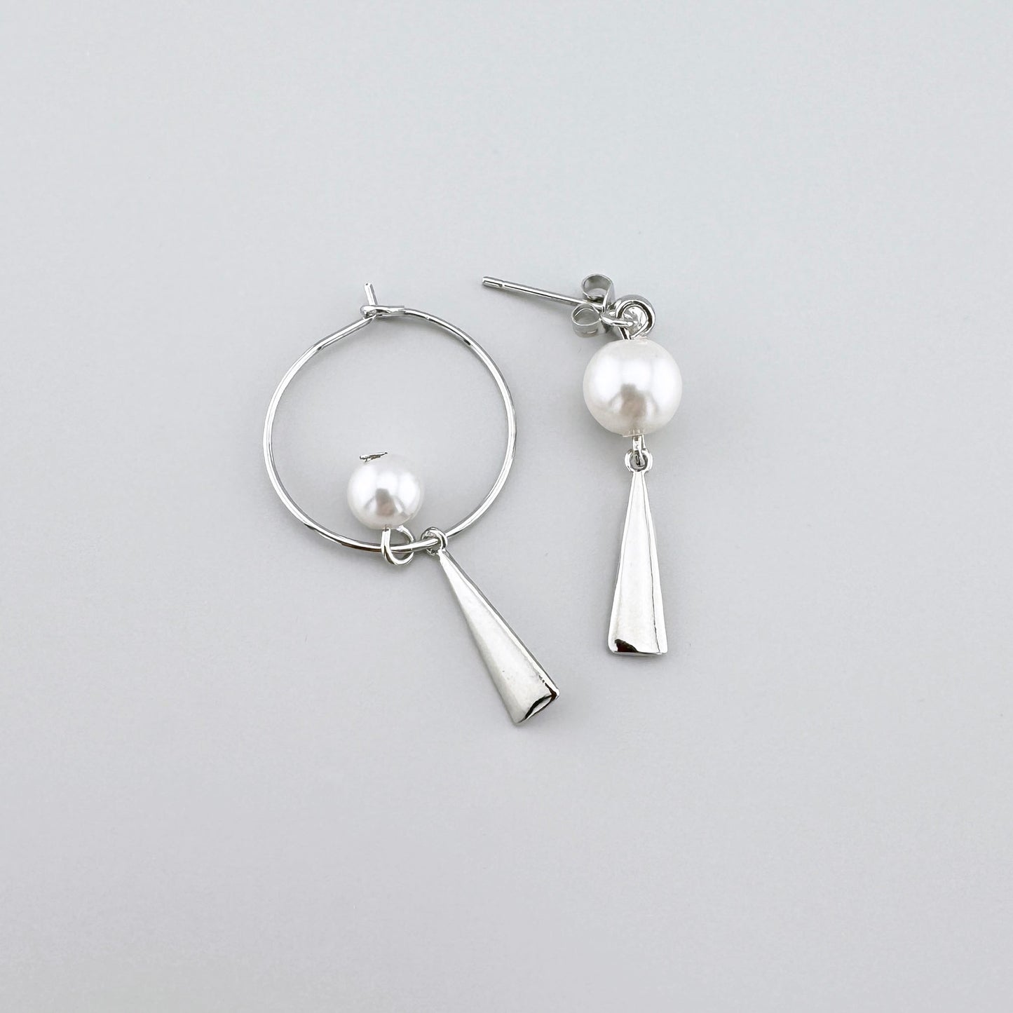 Boucles d'oreilles asymétriques avec perle artificielle et élément géométrique.