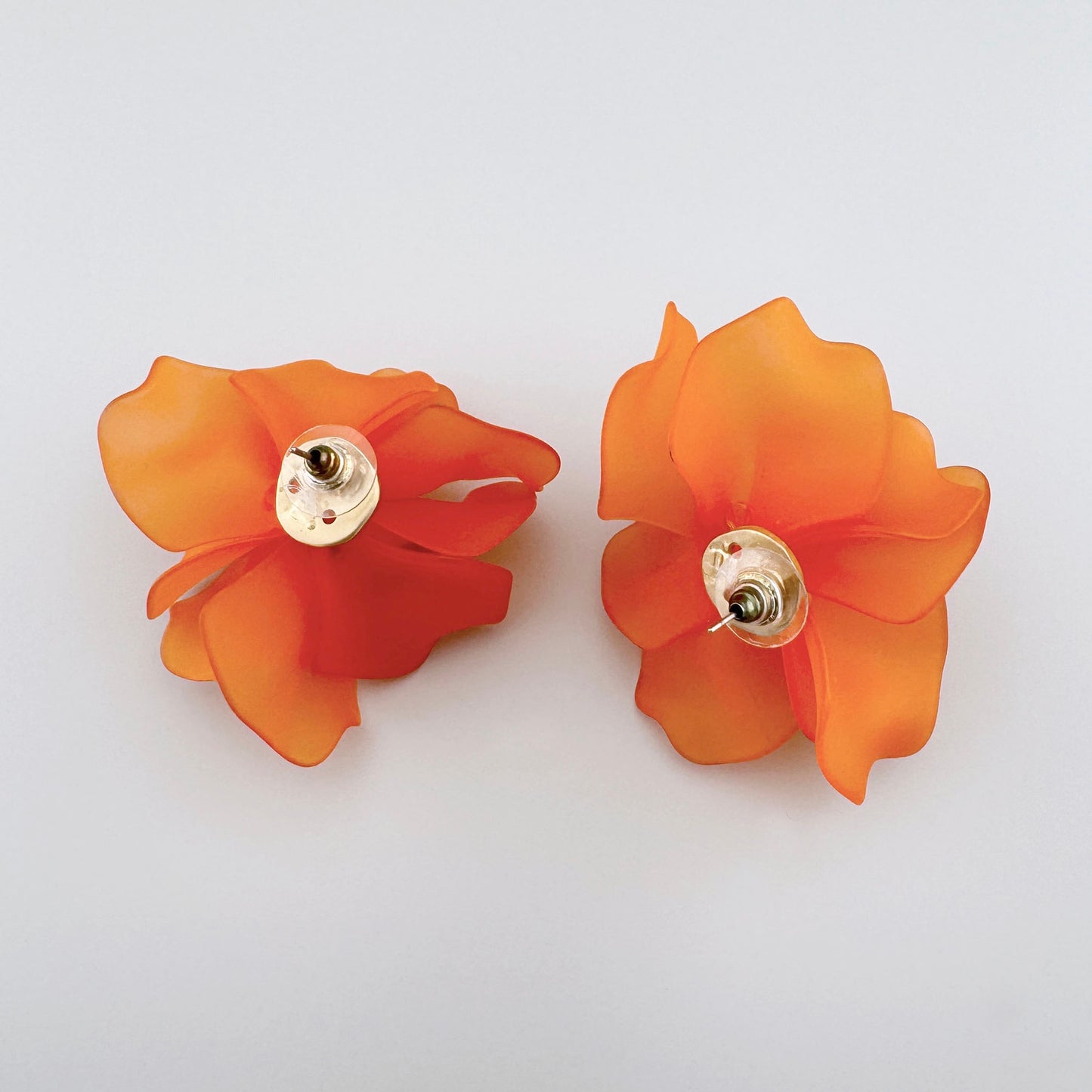 Flower-shaped earrings made of matte acrylic in vibrant orange color.