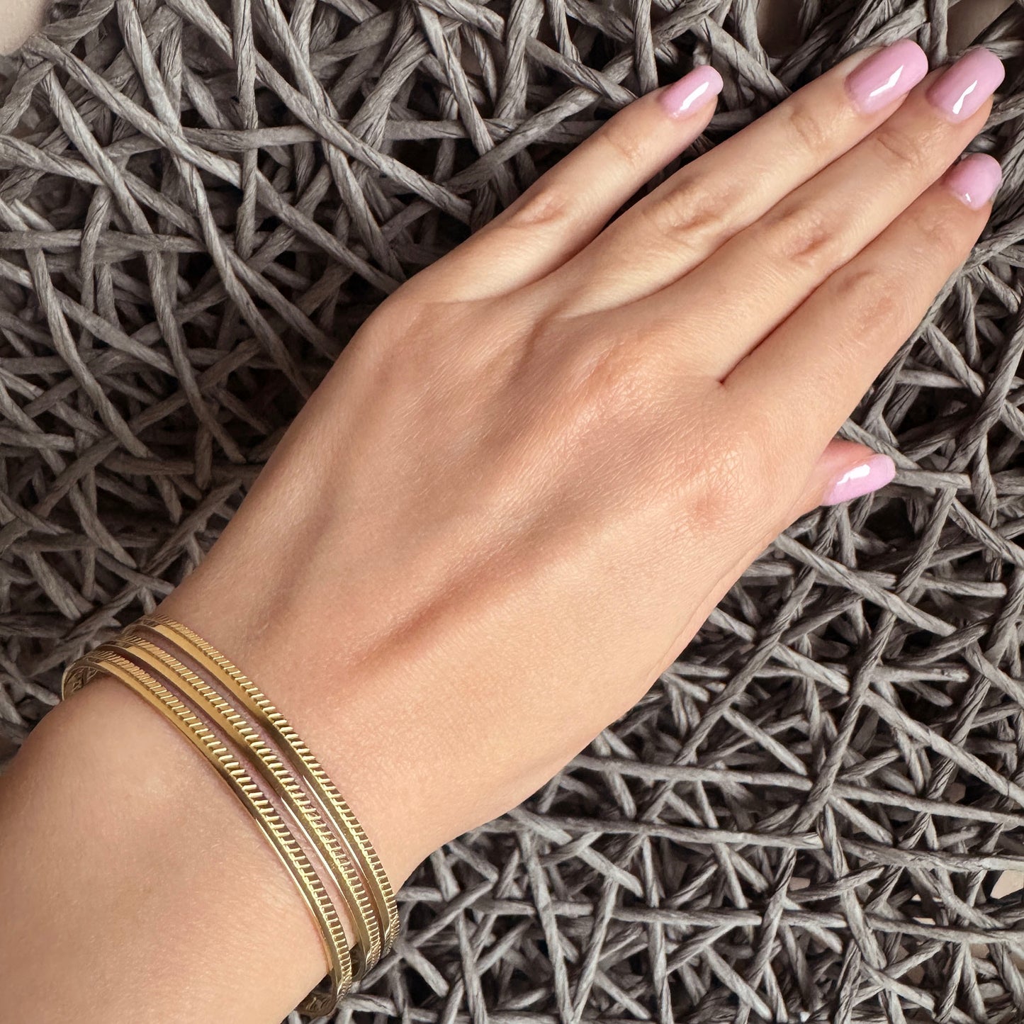 Open bracelet made of gold-plated steel with three thin bands, French brand Ikita.