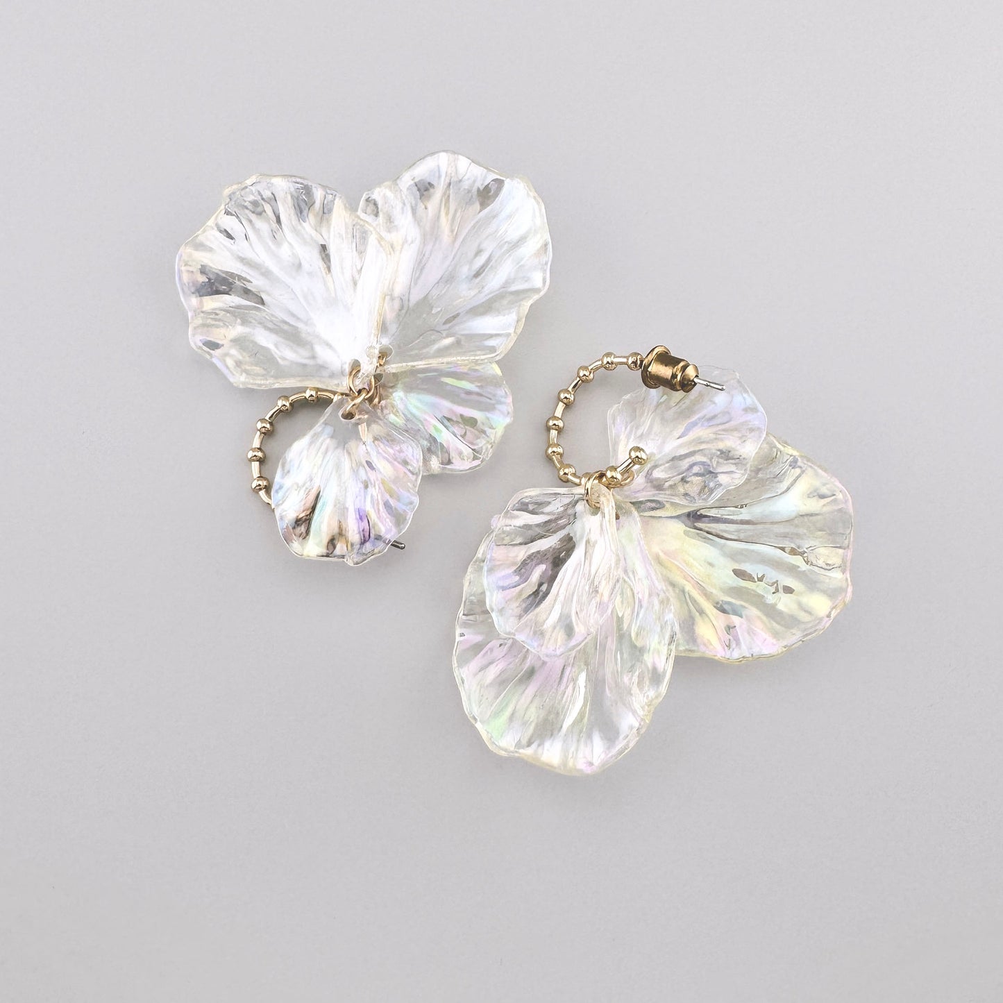 Pendientes con elementos transparentes en forma de pétalos de flores y acentos metálicos dorados.