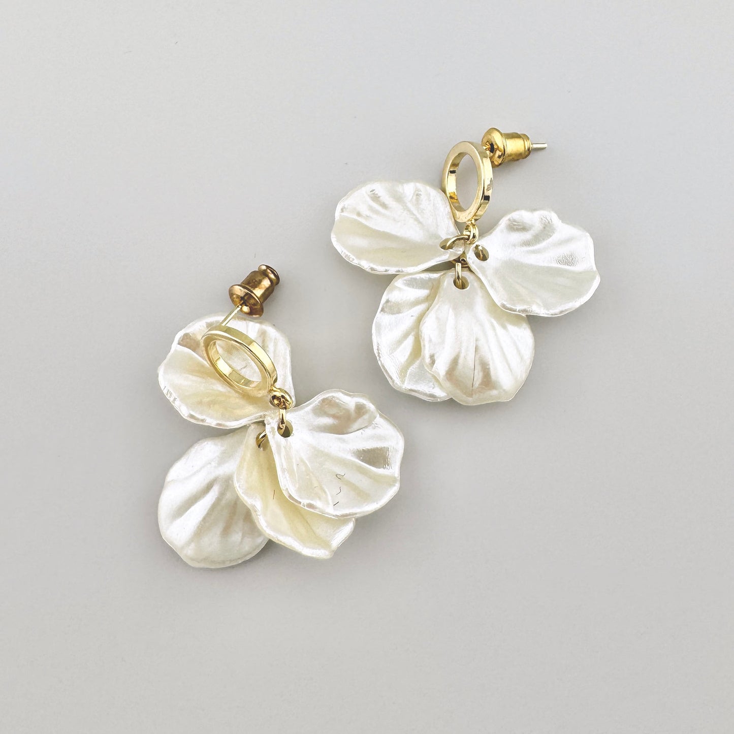 Ohrringe in Perlmuttfarbe mit Blumenmotiven und goldenen Akzenten.