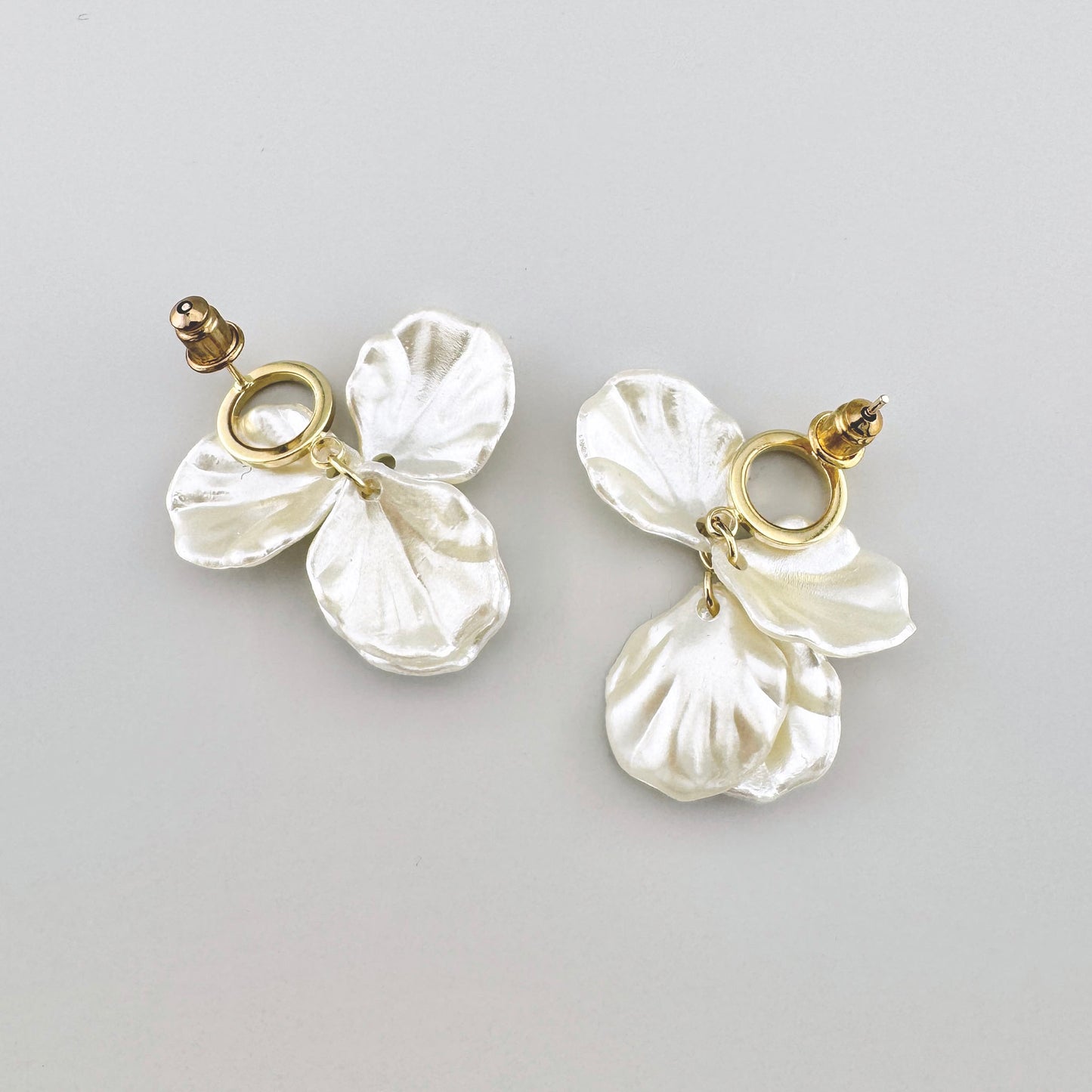 Pendientes en tono perla con motivos florales y detalles dorados.