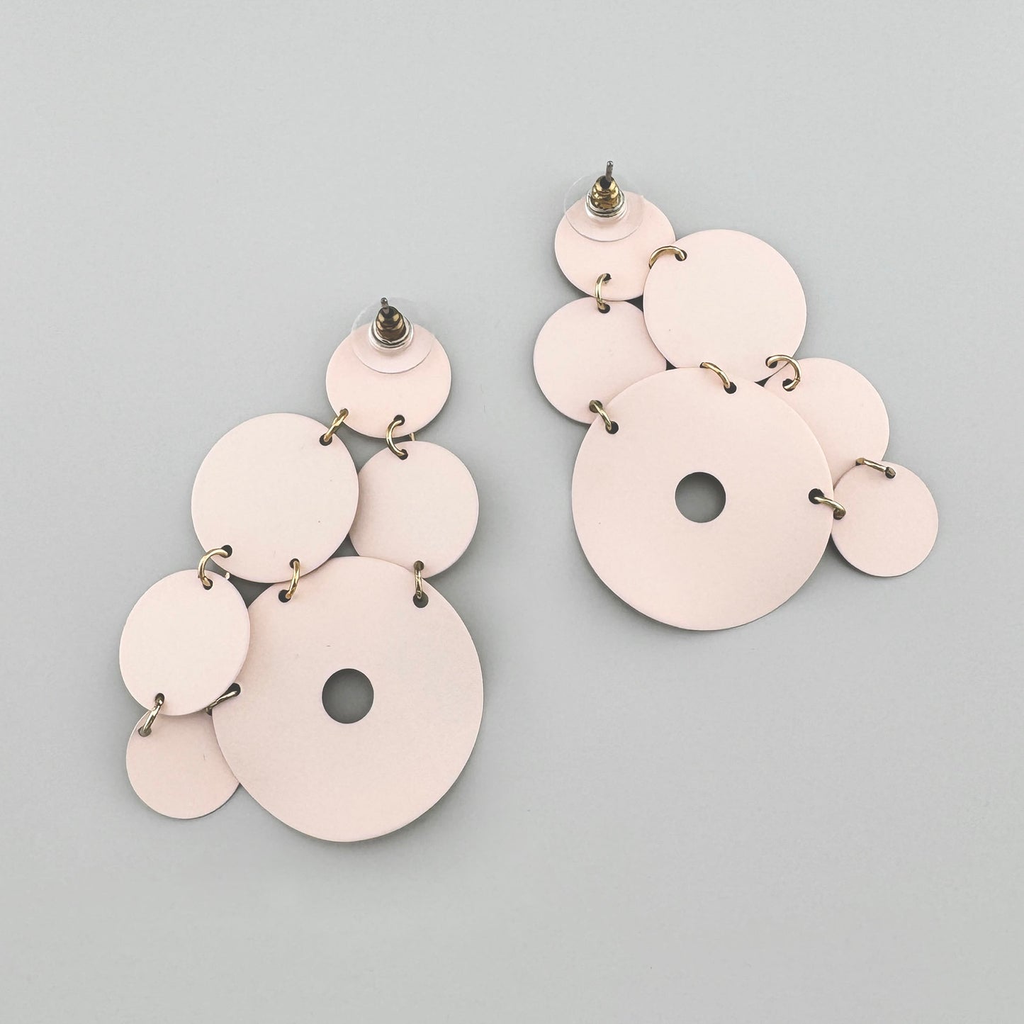 Light pink earrings with geometric circles and a matte finish.
