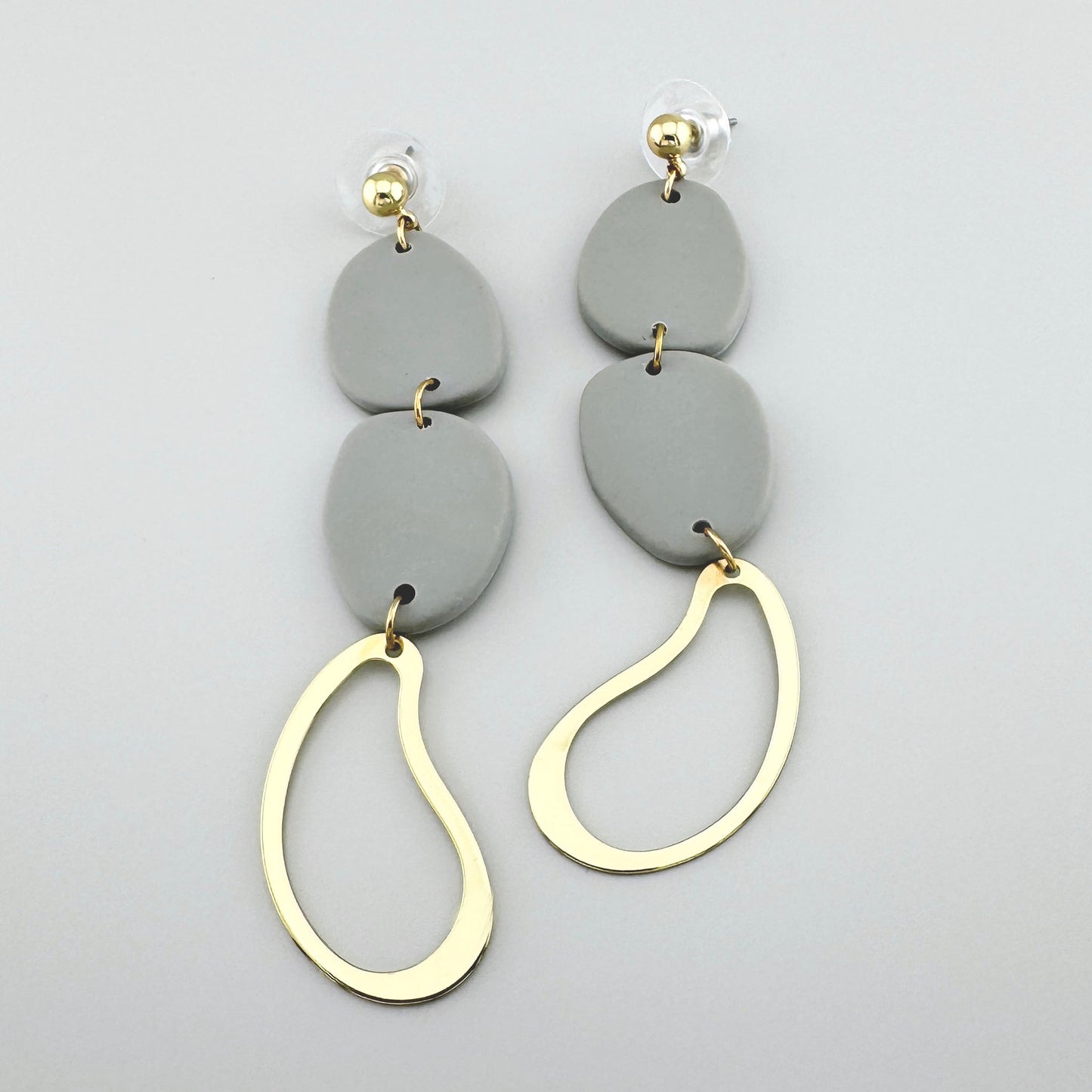 Ohrringe mit grauen Elementen aus Polymer-Ton und goldenen Anhängern in Tropfenform, modernes Design.