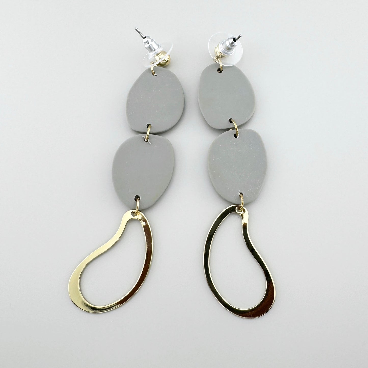 Pendientes con elementos grises de arcilla polimérica y colgantes dorados en forma de gota, diseño moderno.
