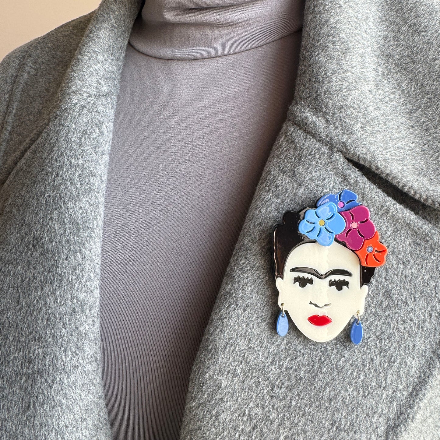 Frida Kahlo portrait brooch with pastel flowers and blue earrings, Spanish brand Sonata.