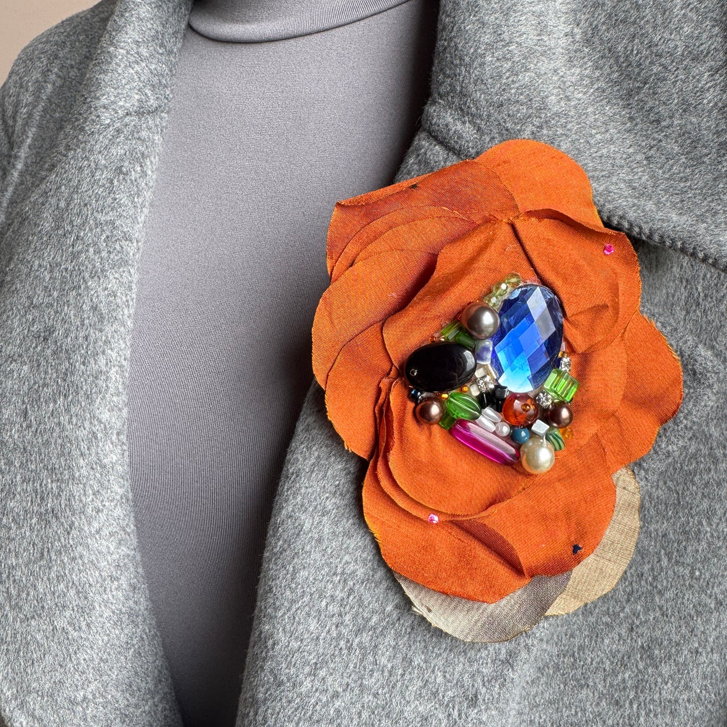 Silk flower-shaped brooch with colorful stones and a large blue crystal, Polish brand BroszArt.