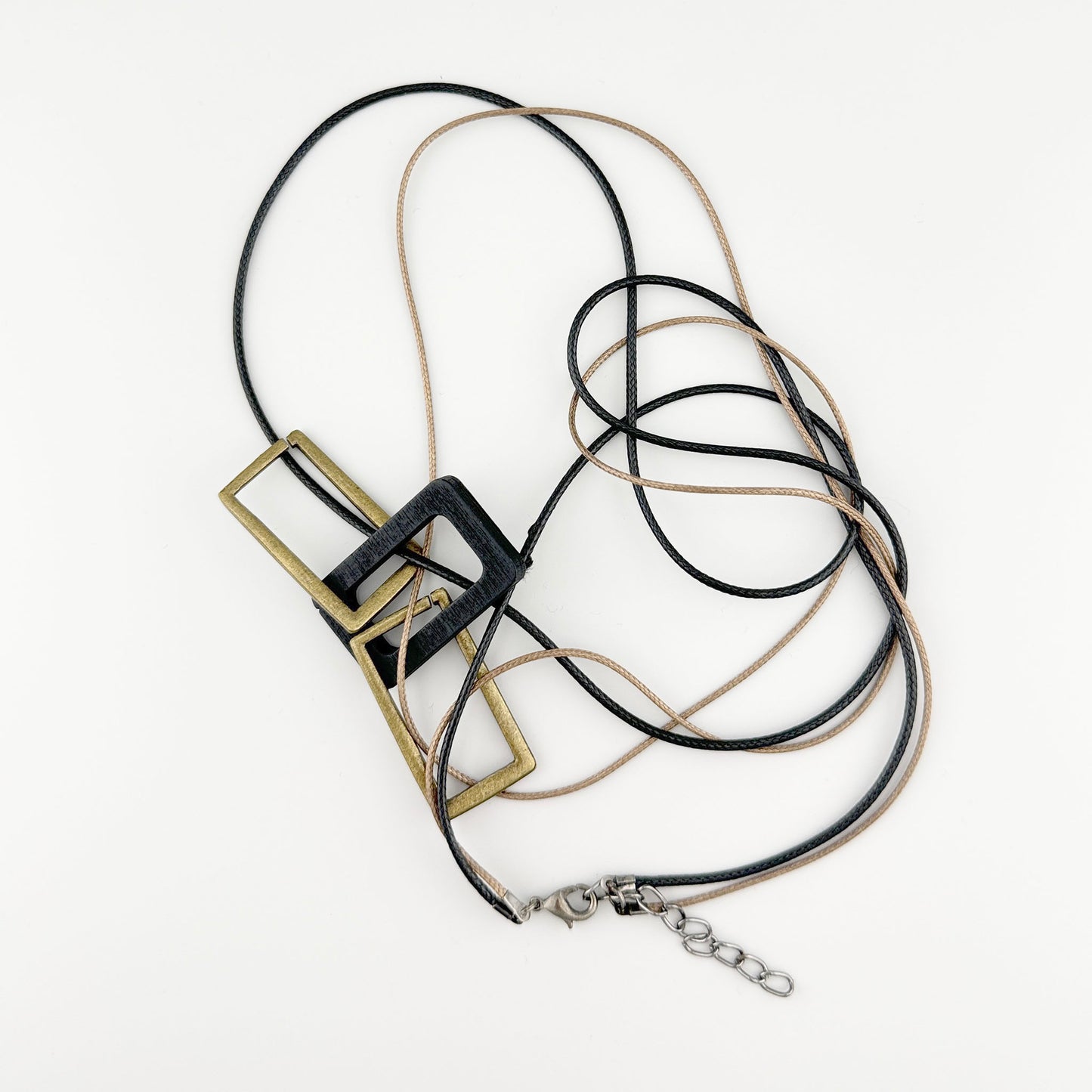 Collar con cordones de cuero negro y beige y colgantes geométricos de metal y madera, marca española Sonata.