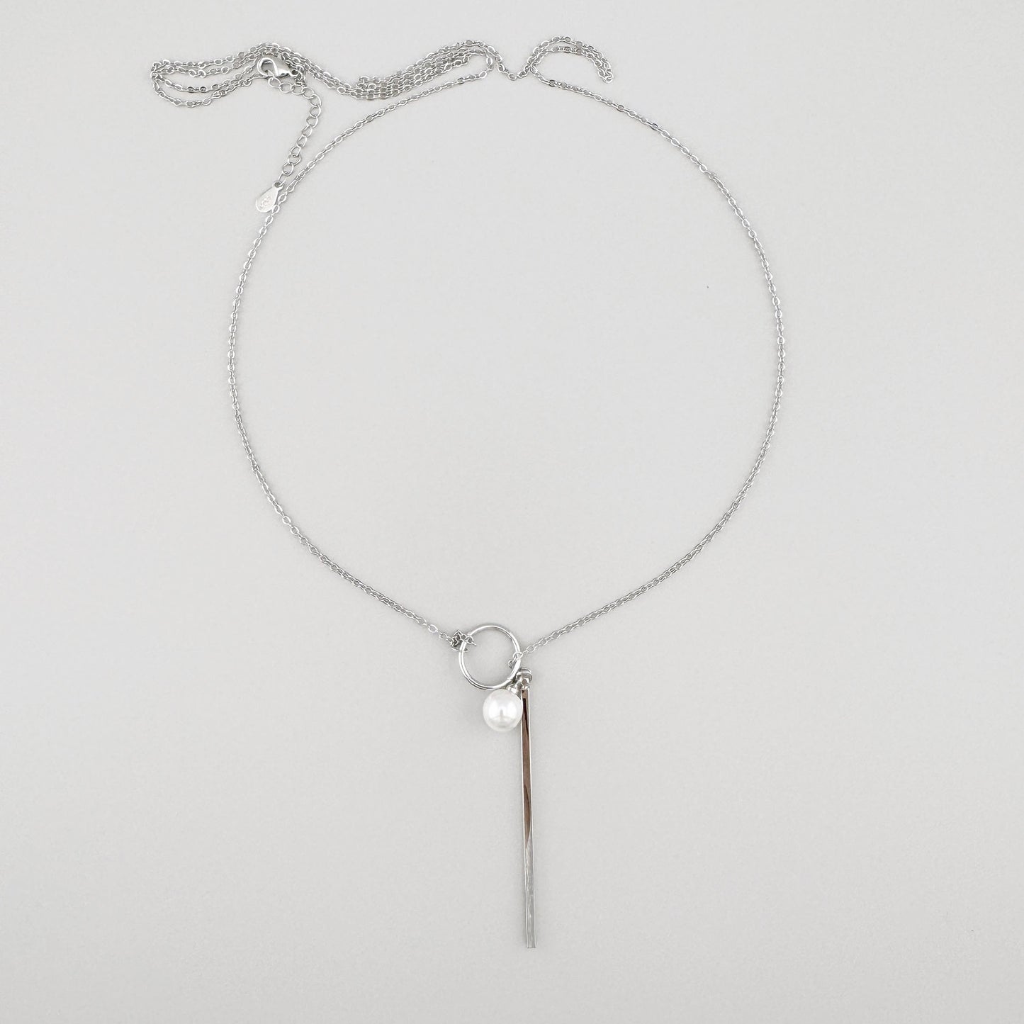 Silberfarbene Halskette mit einer zarten Perle und einem langen hängenden Element, spanische Marke Maravillas.