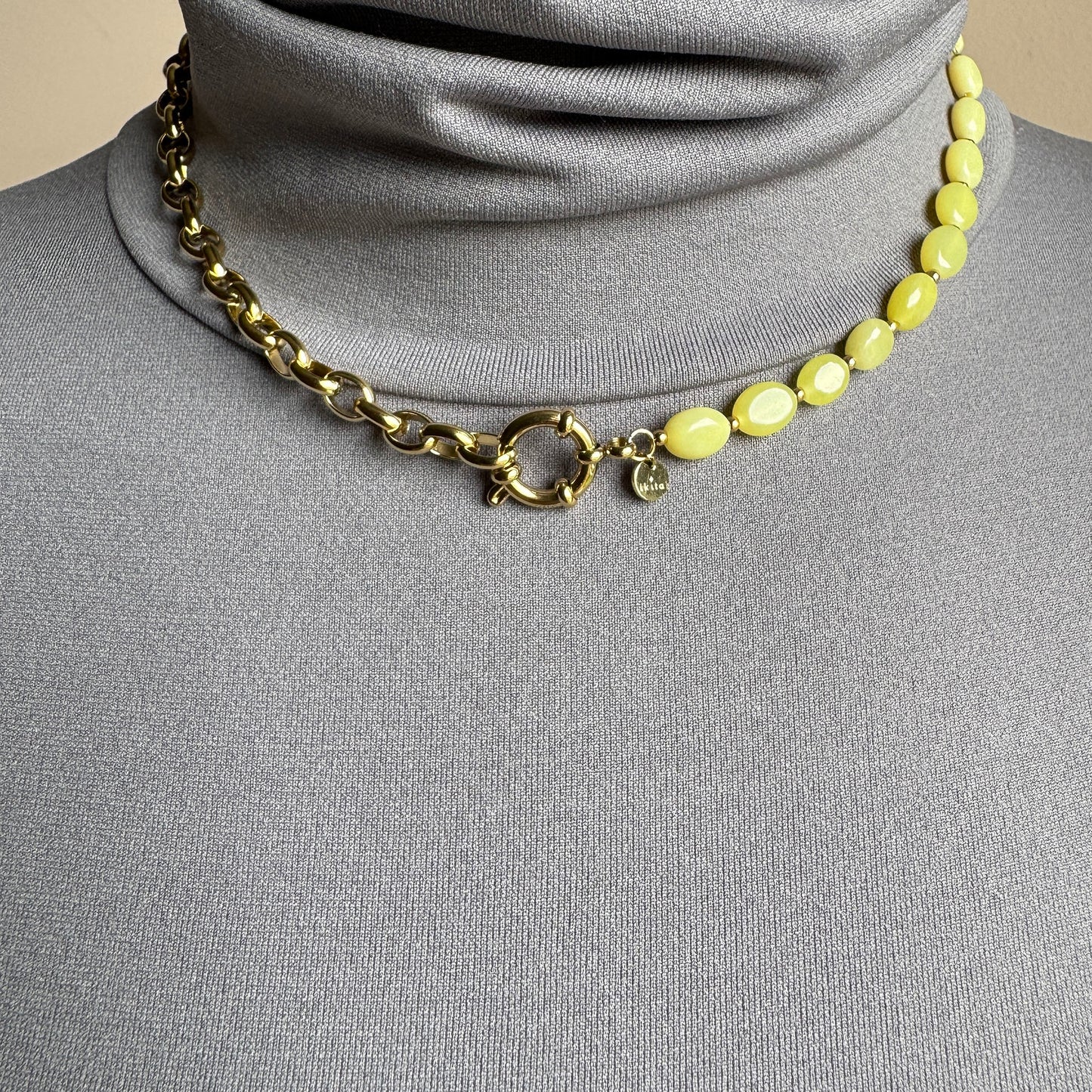 Asymmetric necklace with lemon-yellow jade stones and gold chain, French brand Ikita.