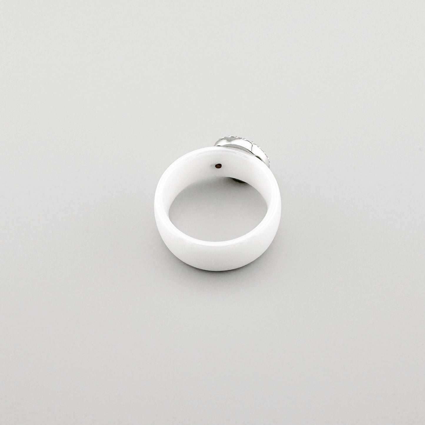 White ceramic ring with a round stainless steel element adorned with cubic zirconia, French brand Cannelle.