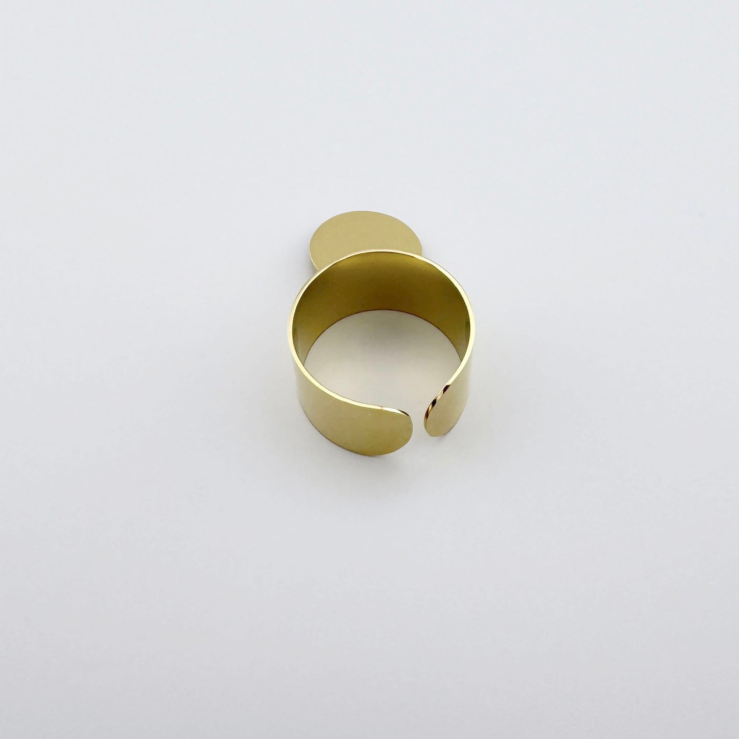 Gold-tone stainless steel ring with a smooth surface and a round charm.