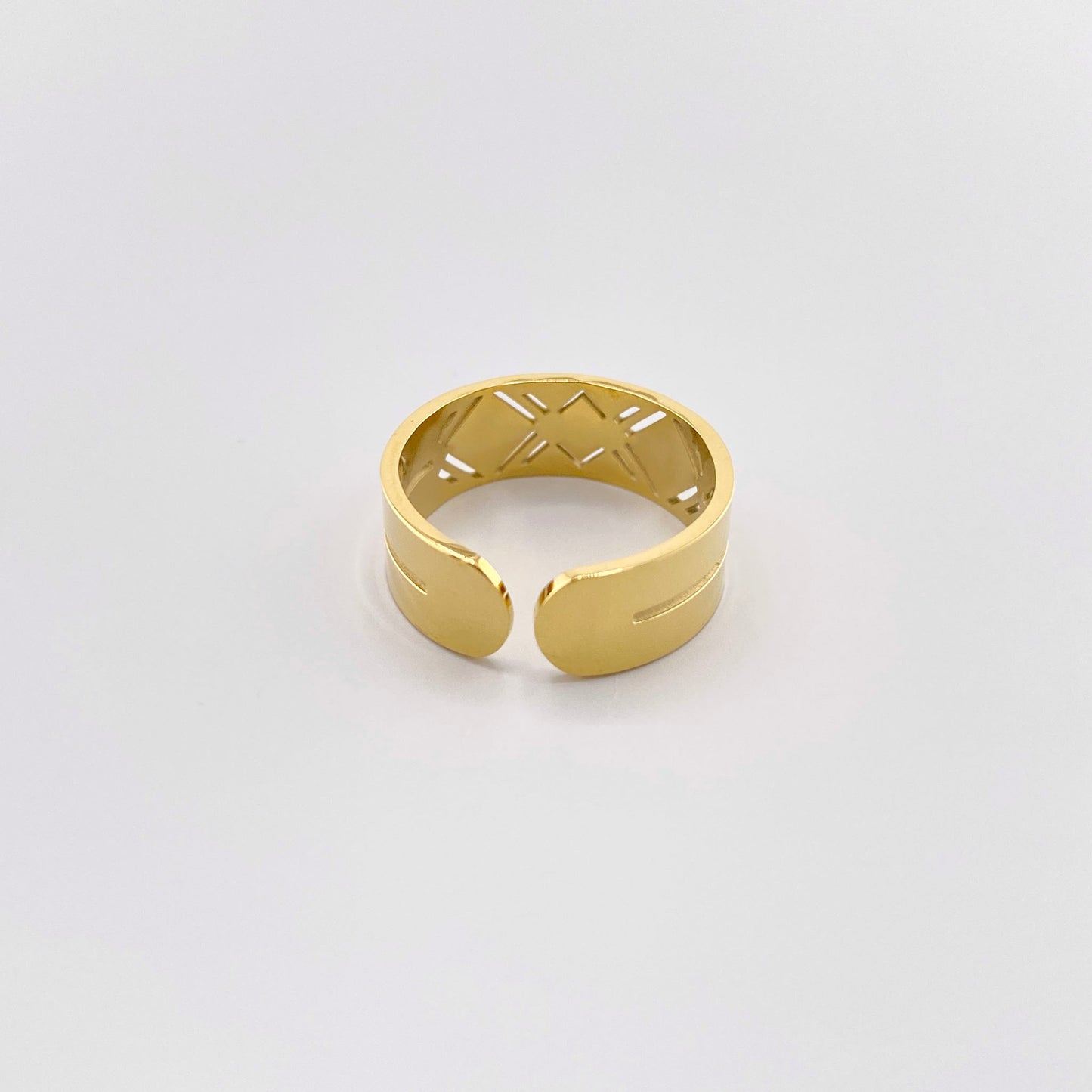 Anillo de acero inoxidable chapado en oro con un diseño geométrico y esmalte blanco, marca francesa Ikita.