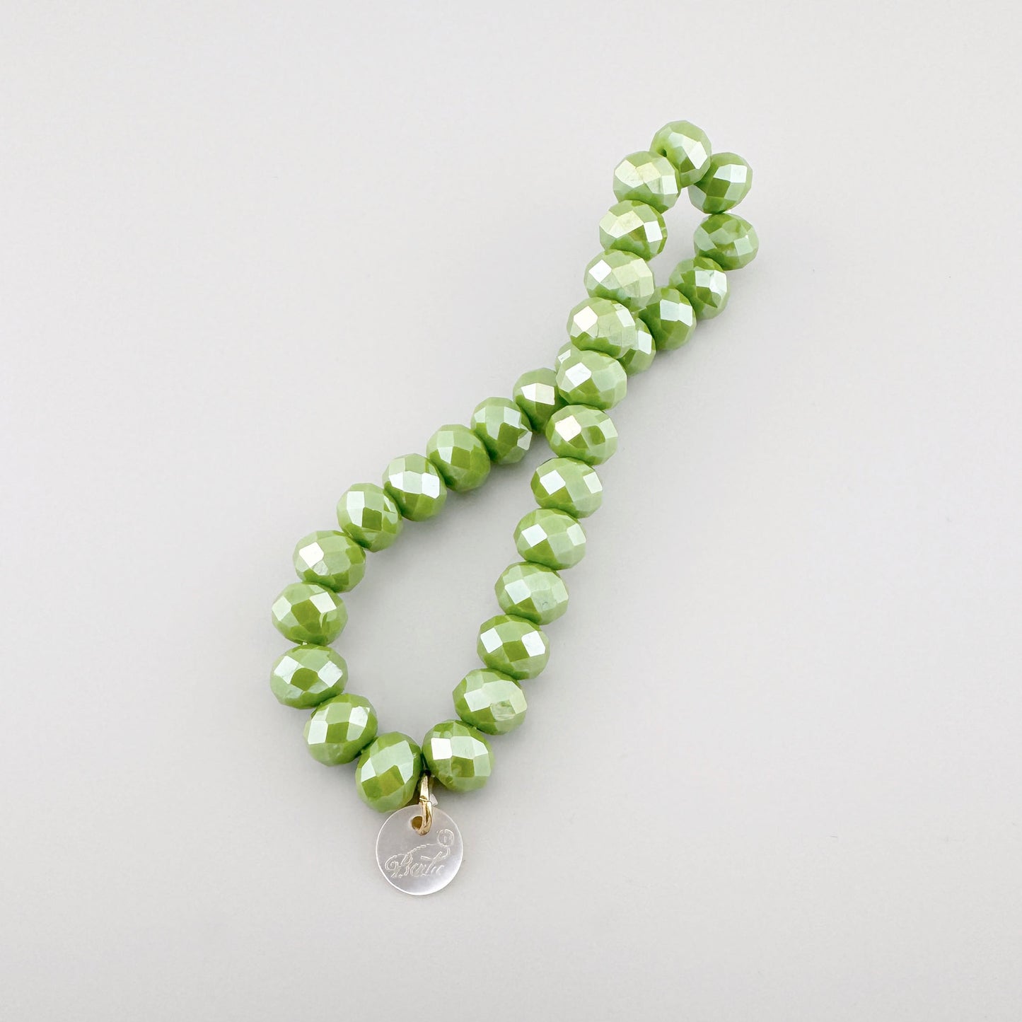 Elastic bracelet with light green faceted beads reflecting light beautifully.